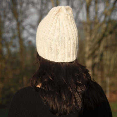 Back view of Cristina in the cream Pampa Cap ethically handmade by artisans for Awamaki knitwear brand based in Peru
