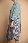 Side view of the double plaid shirtdress. Long sleeves, oversized fit, drop waist appeal. Low high bottom hem. Hits slightly below the knee.