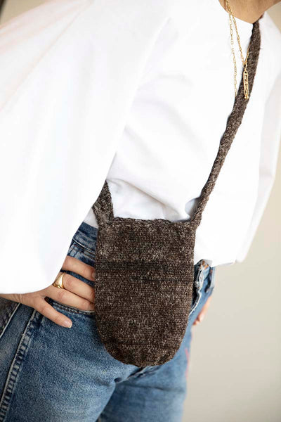 Handcrafted cross body Arhuaca Mochila Bag crochet weaved. Dark brown tone. Shown here as crossbody on a woman wearing a white blouse and vintage Levi Denim.