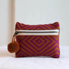 Small handwoven into coin purse made from sheeps wool. Magenta and burnt orange diamond pattern. Features a brass zipper and burnt orange pom pom detail.