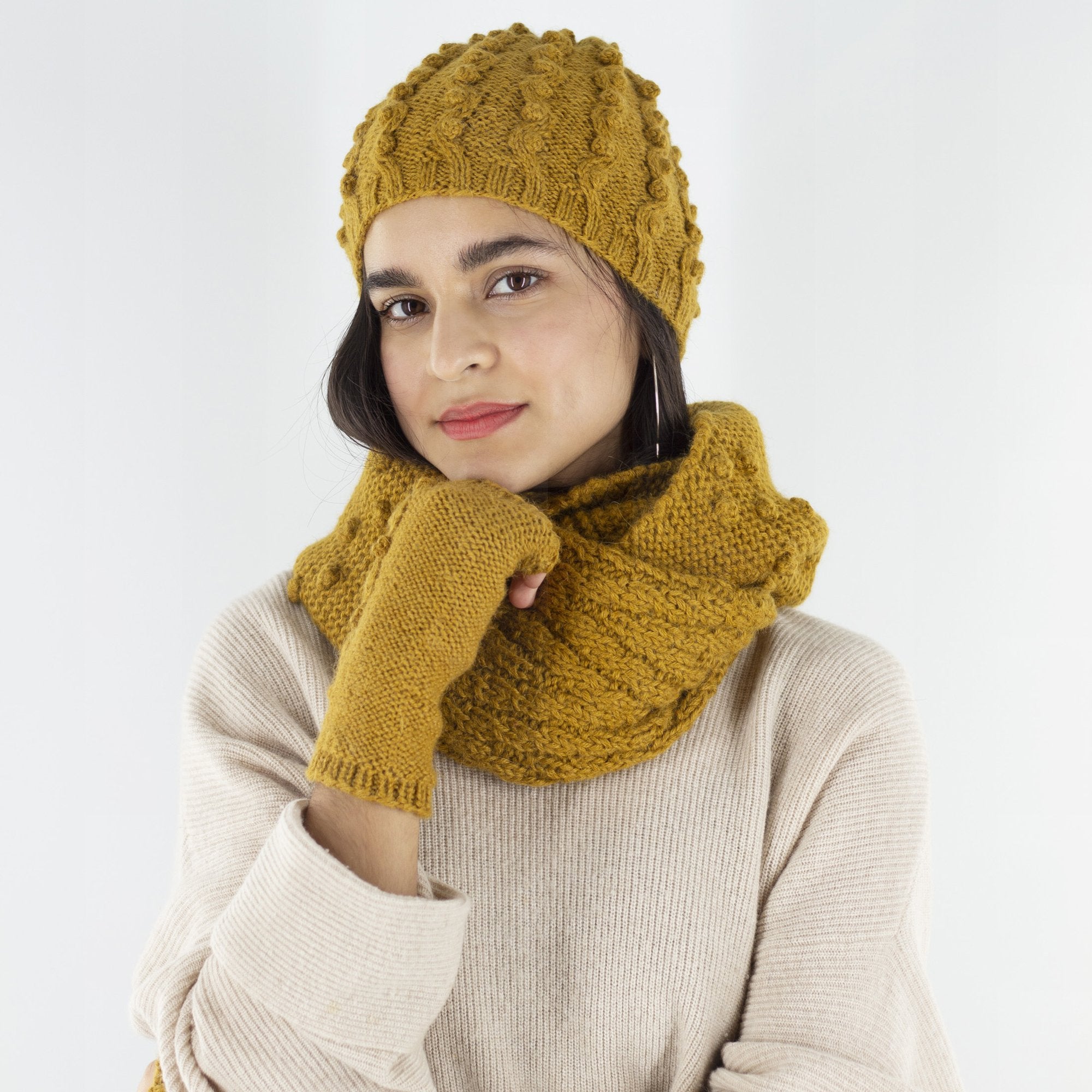 Image of model wearing mustard colored infinity scarf around neck and matching fingerless gloves made from 100% alpaca