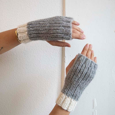 Model wears fingerless hand knitted gloves in grey by Awamaki