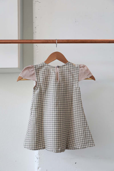 Back view of the pink plaid dress with grey and cream plaid print and loophole closure detail with a wooden button