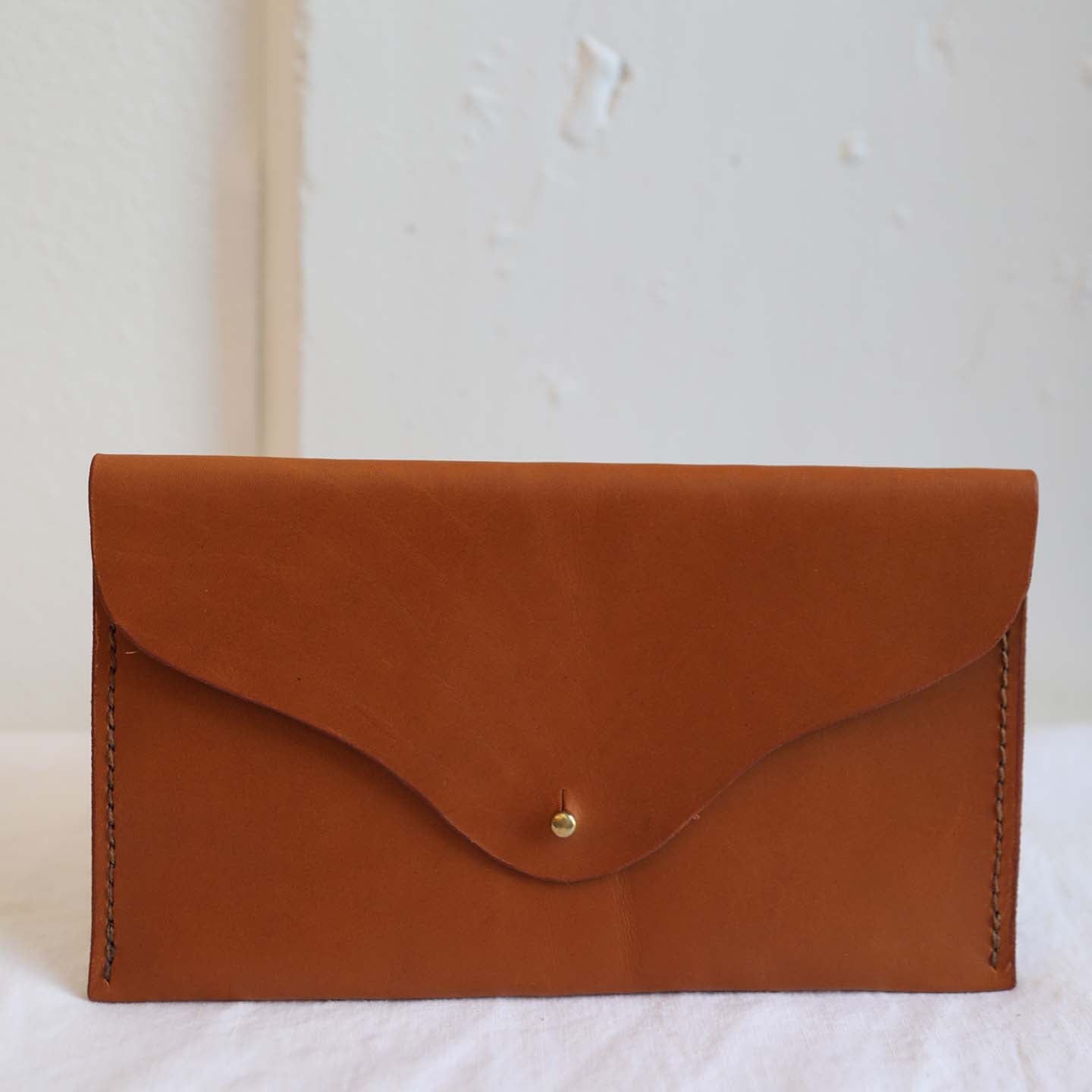 Ethically made caramel leather rectangle clutch with fold over flap and brass closure