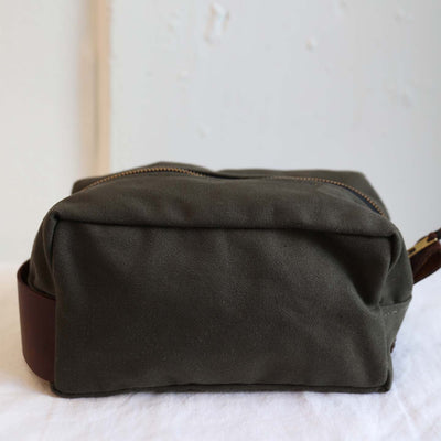 The Evergreen Dopp Kit ethically made by Haiti Design Co features brass hardware and dark leather accents
