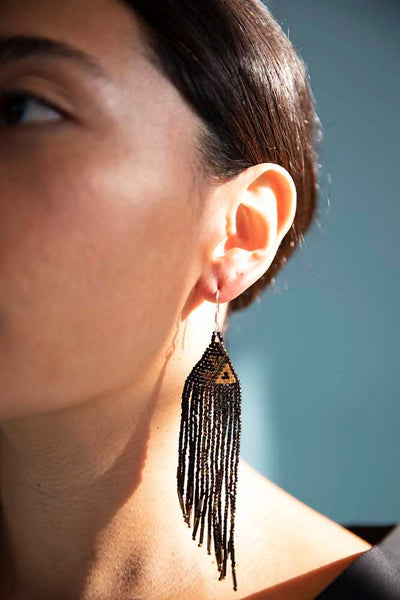 Up close of asymmetrical hand beaded earrings fair trade and made from small black and gold japanese crystal beads