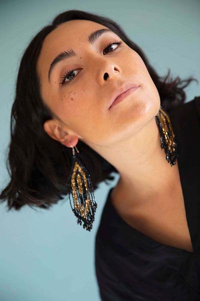 Brunette model with short hair wears sustainably made beaded earrings by Huichol Center in Jalisco, Mexico.