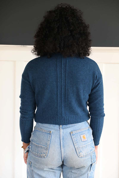 A blue cardigan made from recycled fabrics.  Features 3 lines in middle of back.