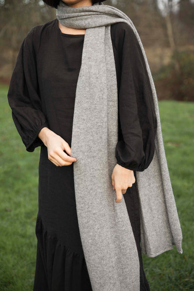 Outdoor shot of woman wearing the black Masako Midi Dress by CURA paired with a grey cashmere scarf ethically made by Joyride Supply
