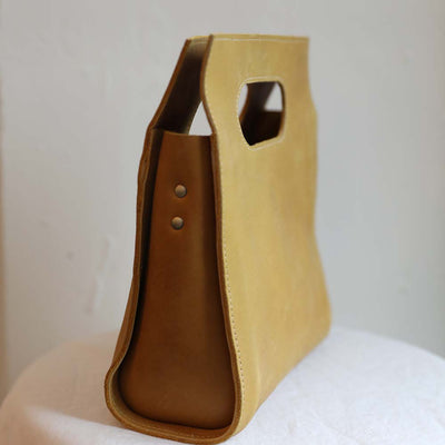 Side view of square leather cutout handle purse in mustard ethically made by artisans in Ethiopia