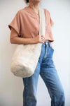 Large crossbody Mochila Bag in a cream color. 100% handspun wool worn here on a woman with a pink shirt, vintage denim.