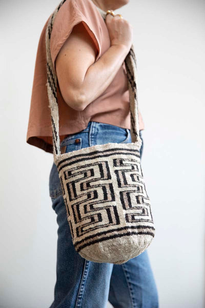 Handcrafted cross body Arhuaca Mochila Bag crochet weaved. Cream and brown color palette. Shown here as crossbody on a woman wearing an upcycled pink crop top and vintage Levi Denim.