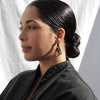 Profile view of woman with low bun wearing Calypso Earrings in black by South African atelier, Pichulik
